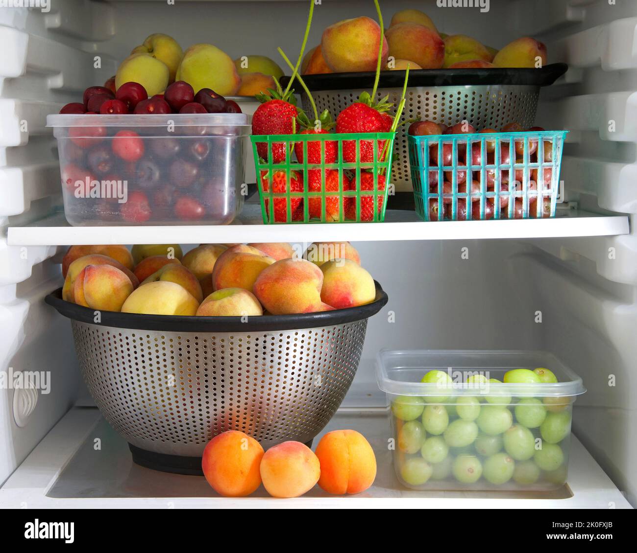 Frigorifero domestico con contenitori di frutta fresca da giardino, pesche, uva, ciliegie, fragole e nettarine. Spuntini salutari. Foto Stock