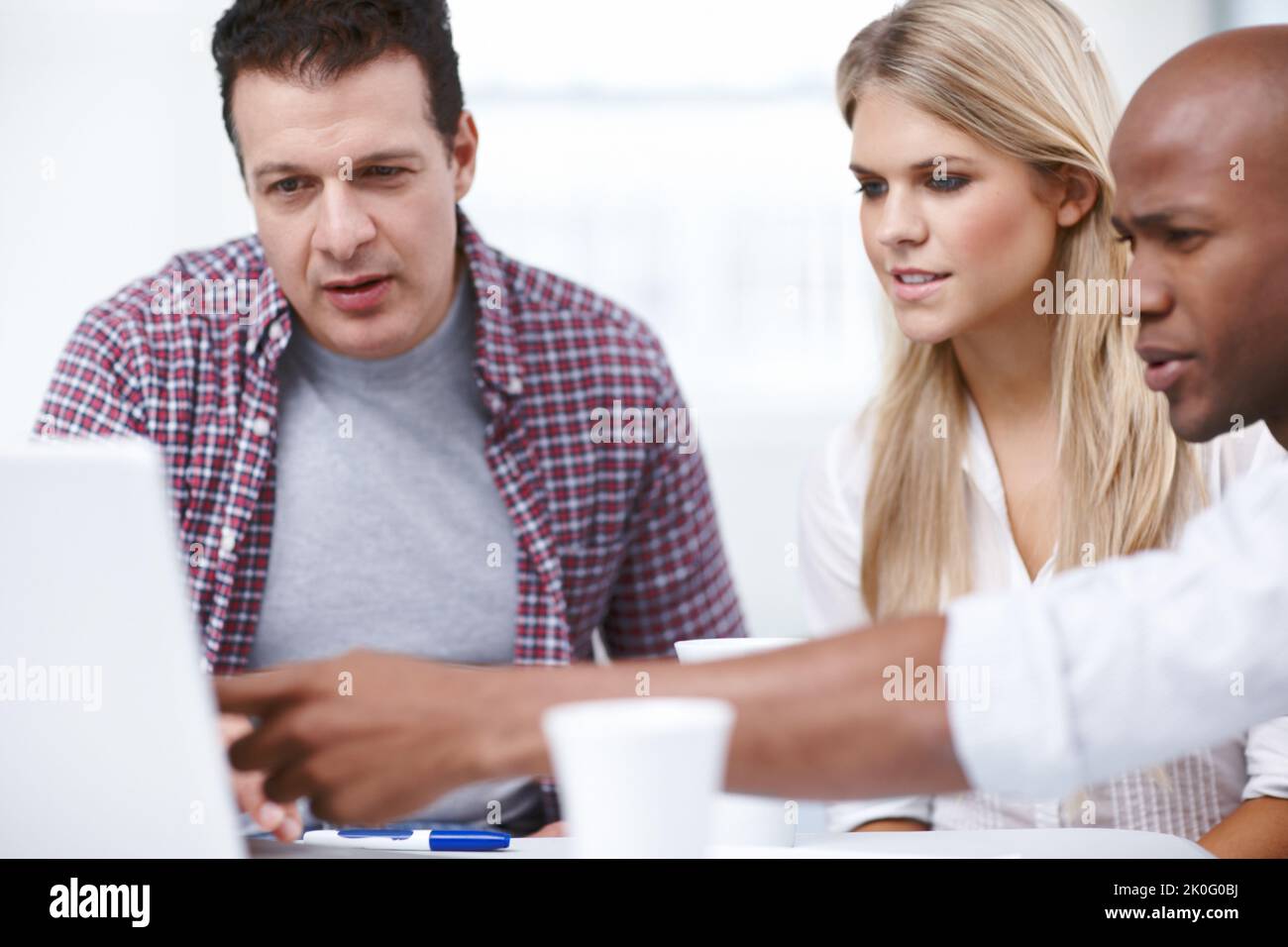 Abbiamo un piccolo problema qui...tre professionisti del design che lavorano insieme a un progetto su un notebook. Foto Stock