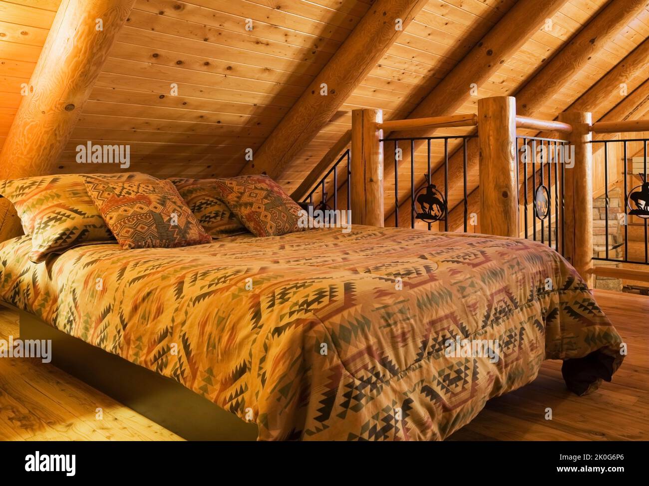 Letto queen size con copriletto a motivi Navajo nella camera da letto degli ospiti al piano superiore all'interno della casa in tronchi in stile cottage scandinavo. Foto Stock