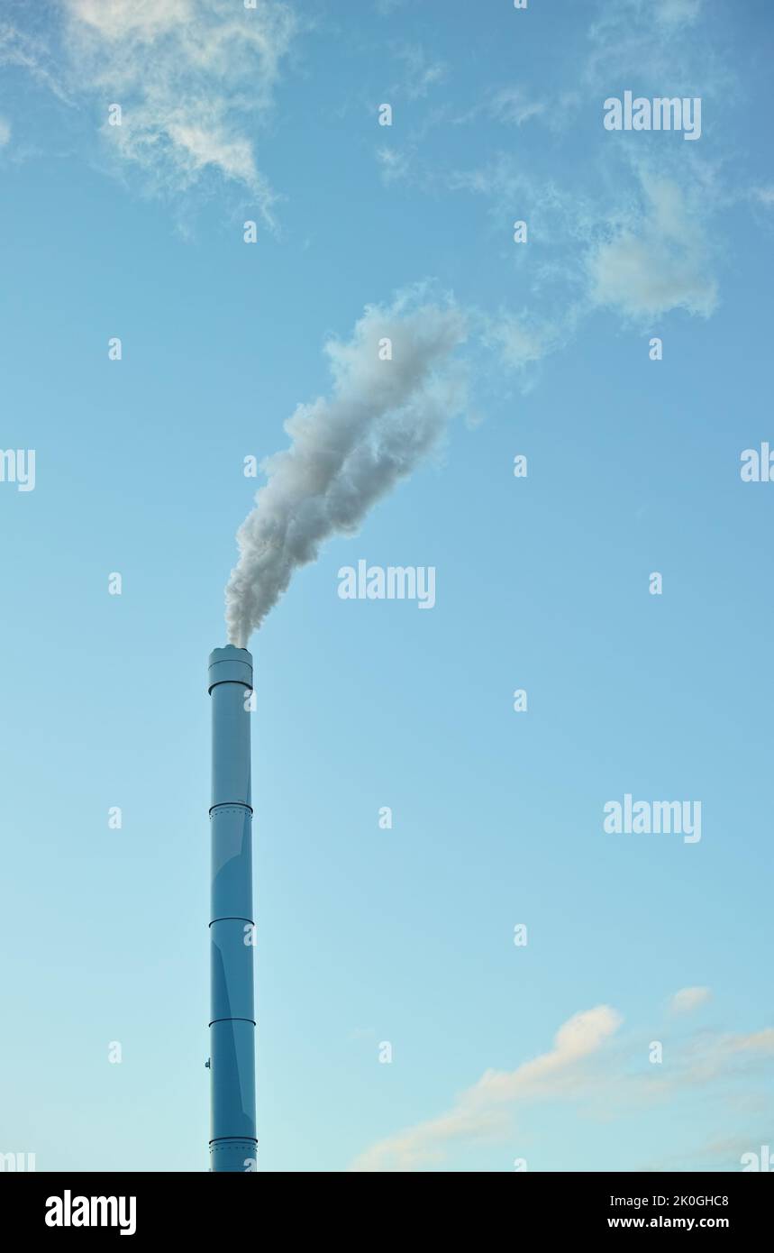 Industria dell'inquinamento. Un camino di fabbrica con fumo che si billowing nell'aria. Foto Stock