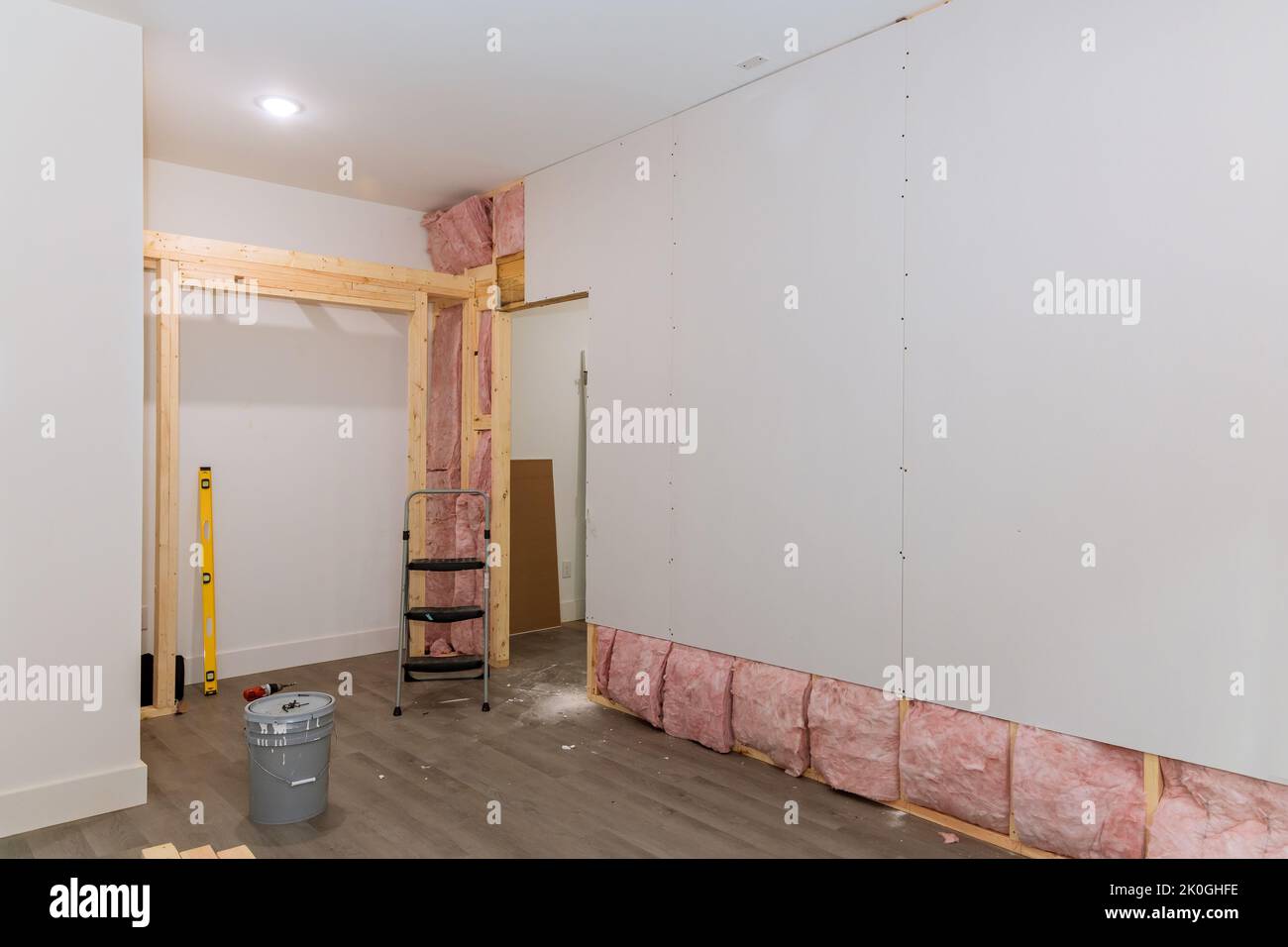 Dopo aver installato l'isolamento termico e acustico per una nuova casa, il muro a secco viene avvitato alle pareti sulla cornice delle travi Foto Stock