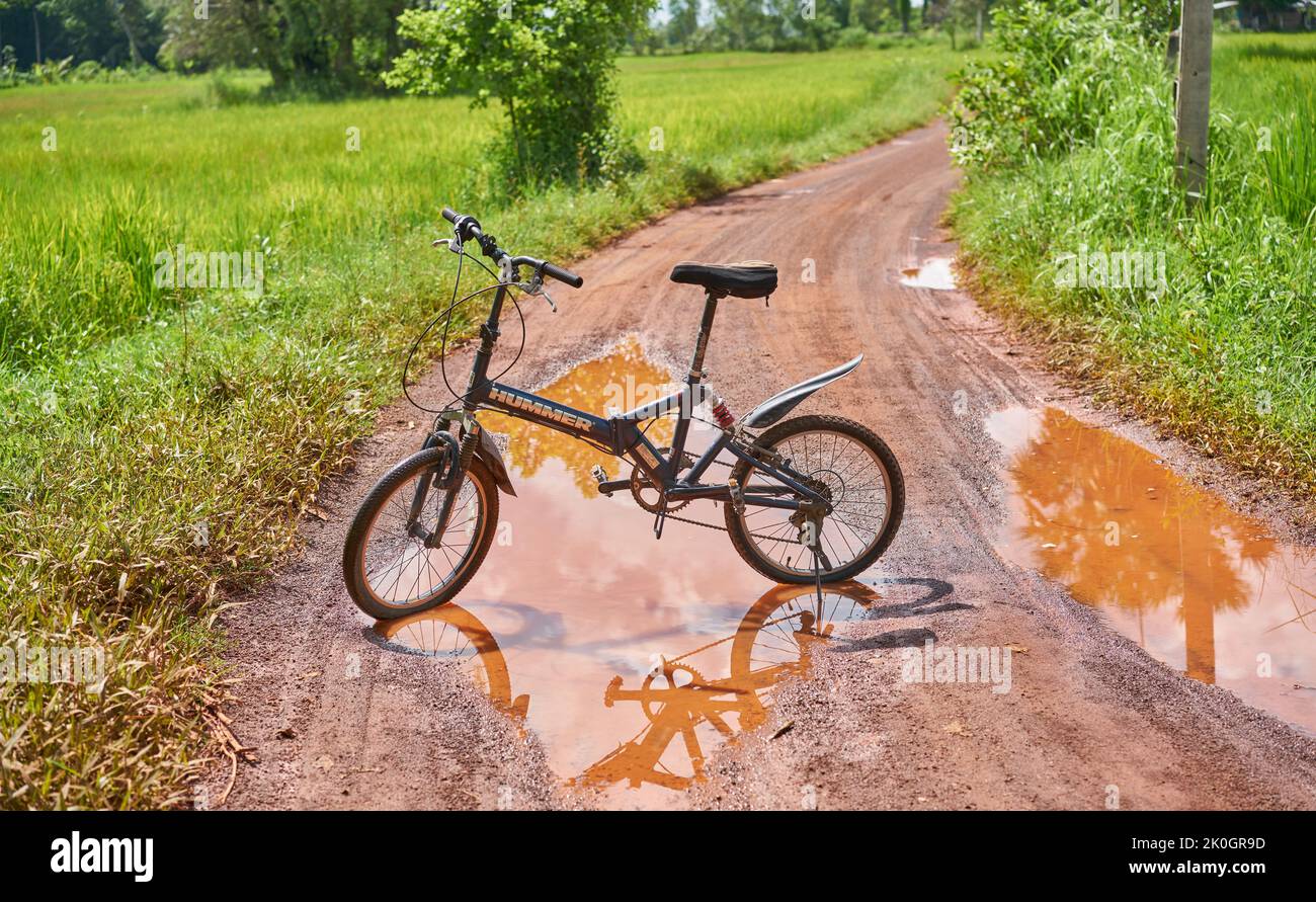 Una bicicletta di montagna e riflessione in una pozza d'acqua su una strada di campagna. Foto Stock