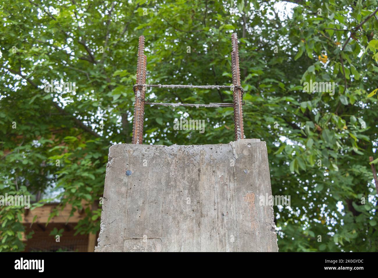La colonna di cemento di recente costruzione per la casa futura da vicino - circondata da alberi verdi Foto Stock