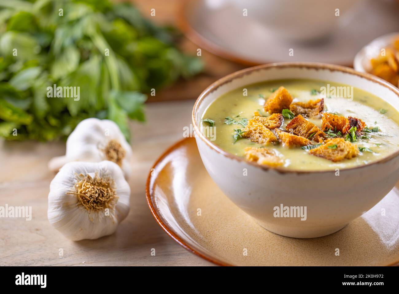 Zuppa all'aglio con crostini di pane e condita con foglie di sedano in coppe. Foto Stock