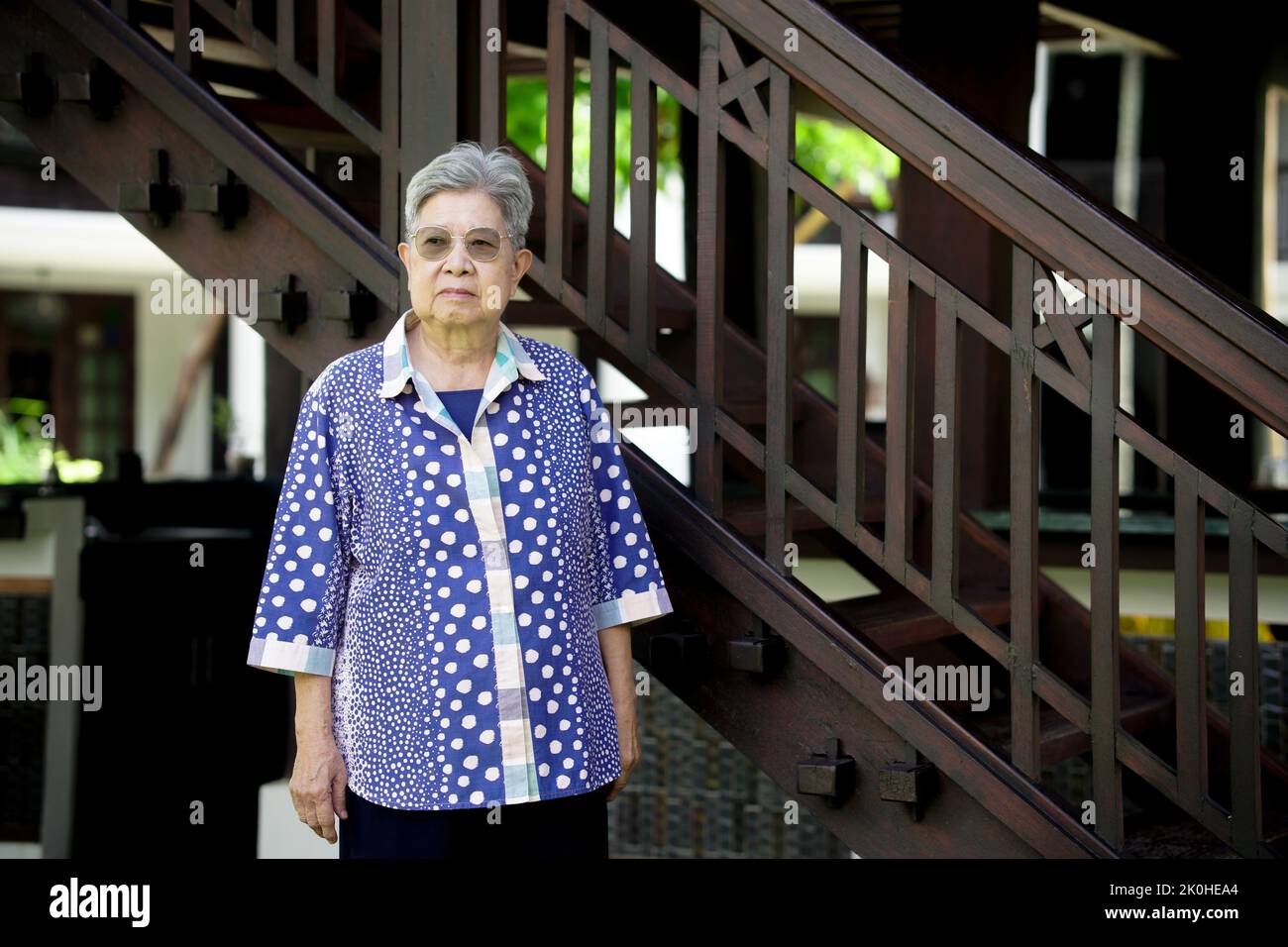 anziana anziana anziana donna anziana che riposa rilassandosi vicino alle scale Foto Stock