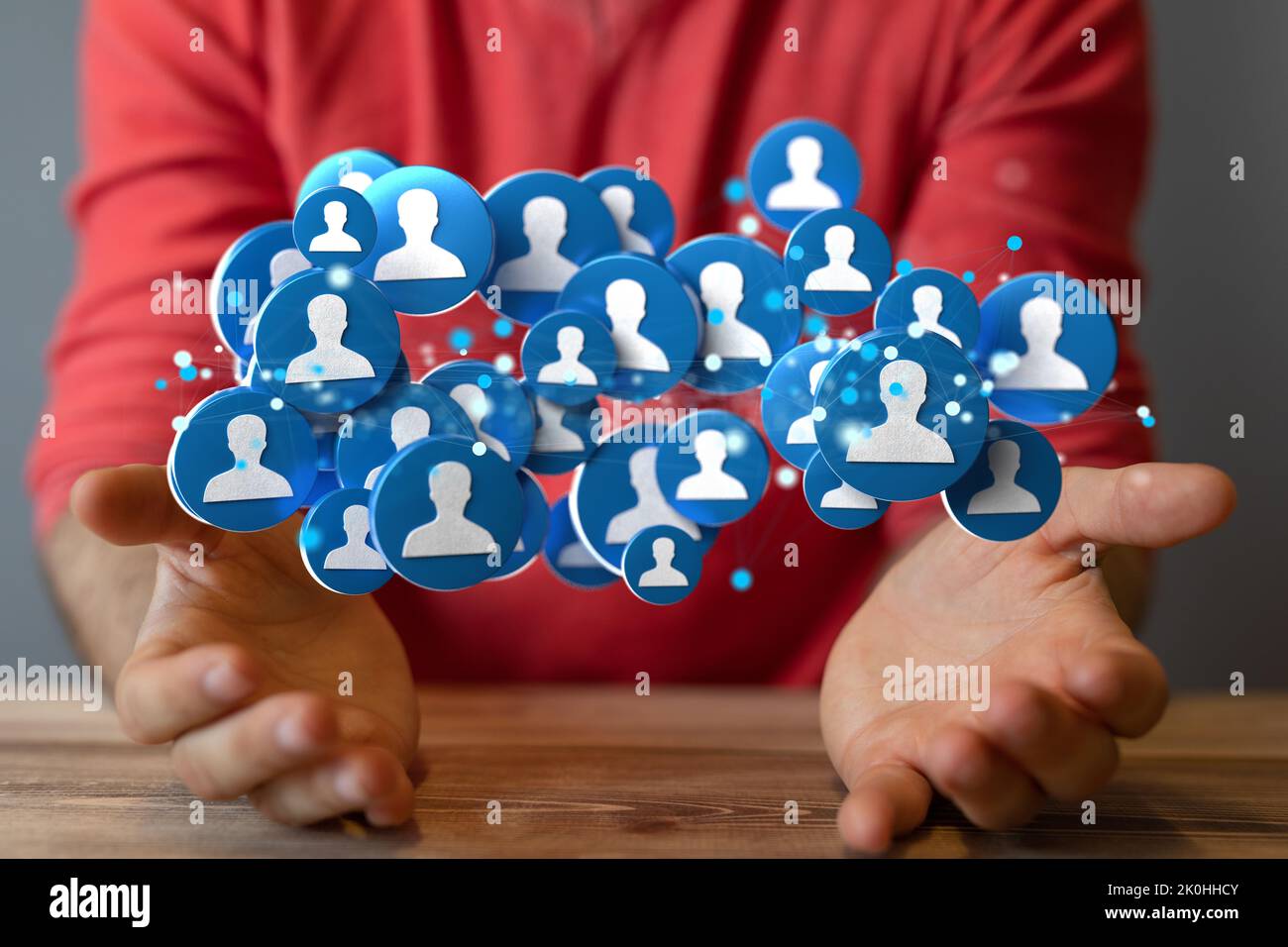 un uomo che tiene una rete di icone con silhouette umane collegate l'una con l'altra. Foto Stock