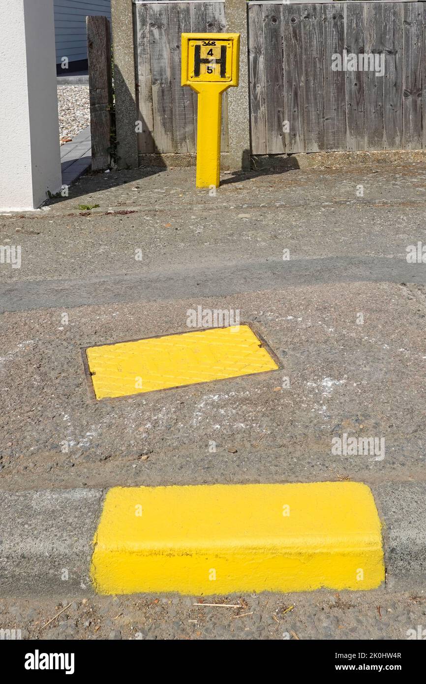 Importante lavoro di manutenzione e verniciatura da parte dei vigili del fuoco Essex di sotterraneo idrante fornitura di acqua giallo manhole copertura segno & marchiatore Inghilterra UK Foto Stock