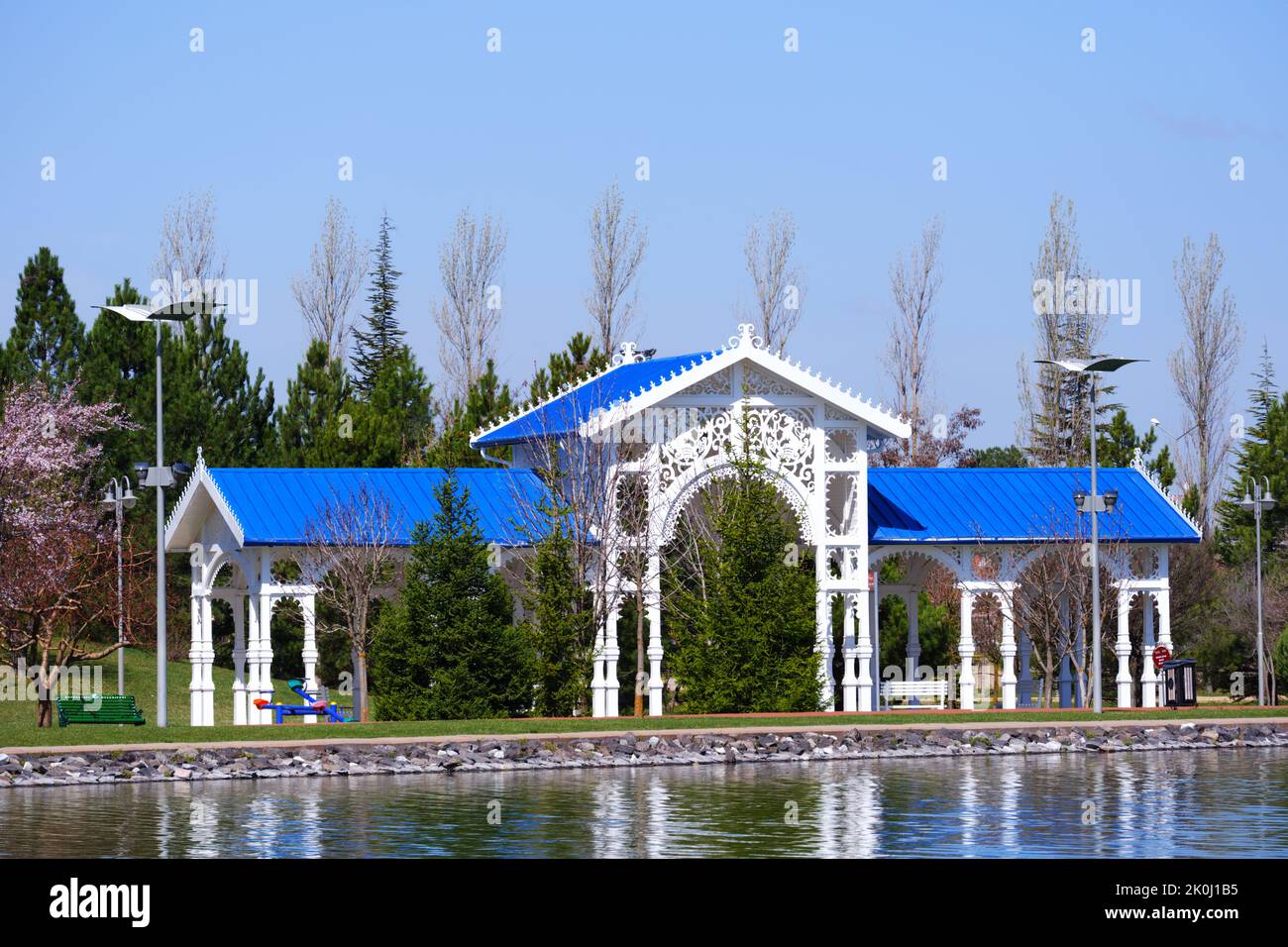 Nostalgica stazione ferroviaria in legno con tetto blu all'interno di alberi lungo il lago in estate Foto Stock