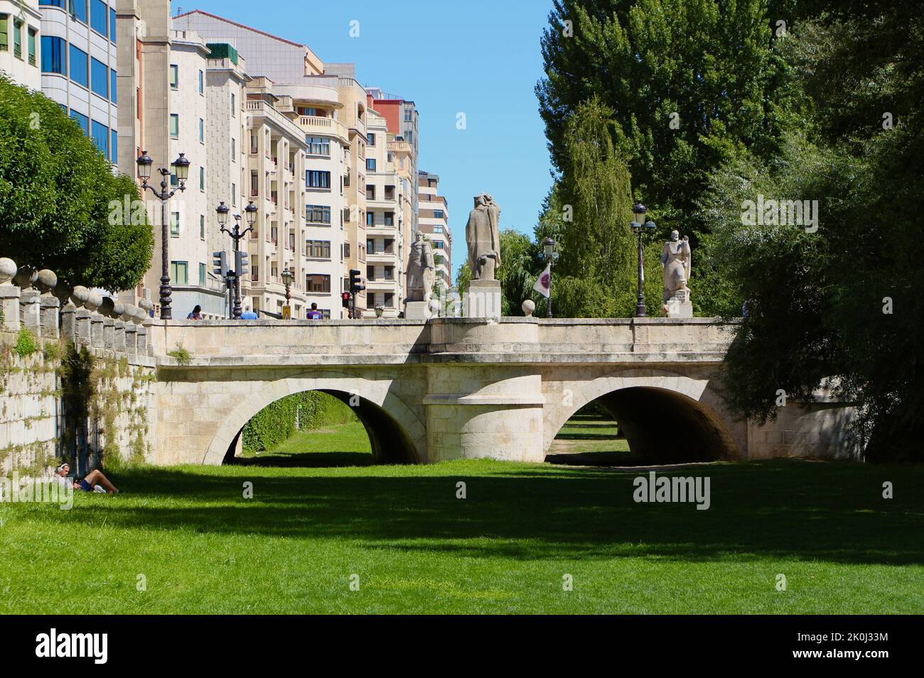 Persona rilassata sull'erba vicino a Saint Marys Bridge sulla riva del fiume Arlanzon Burgos Castiglia e Leon Spagna Foto Stock