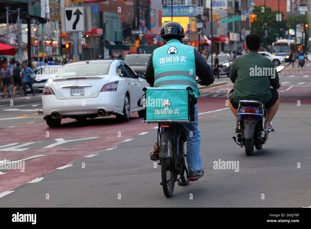 Una persona Fantuan Delivery su una bicicletta elettrica nel centro di Flushing, New York. Fantuan 飯糰外賣 consegna di cibo asiatico Foto Stock