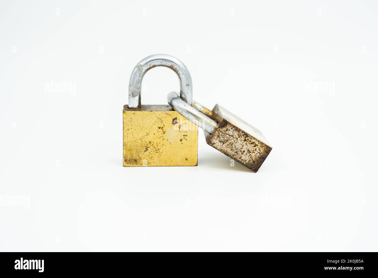 Due vecchi lucchetti color oro bloccati e collegati l'uno all'altro posti in posizione verticale Foto Stock