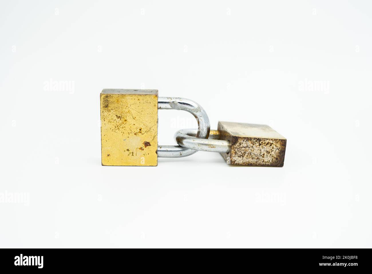 Due vecchi lucchetti color oro bloccati e collegati l'uno all'altro disposti orizzontalmente Foto Stock