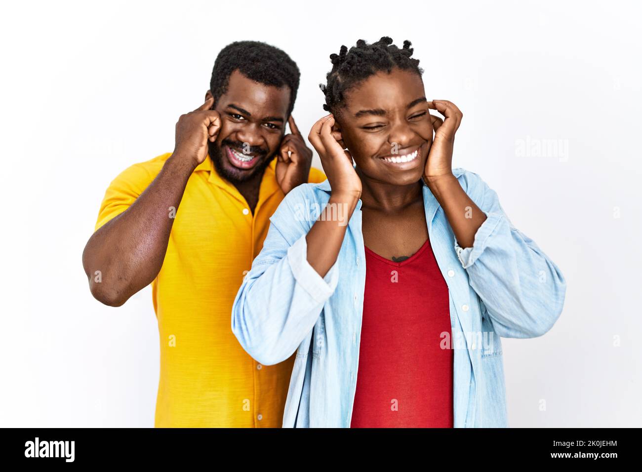 Giovane coppia afro-americana che indossa abiti casual coprendo le orecchie con le dita con un'espressione fastidiosa per il rumore della musica forte. Concetto sordo. Foto Stock