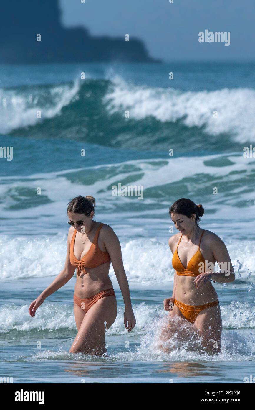 Due femmine in bikini che camminano fuori del mare a Fistral Beach a Newquay in Cornovaglia nel Regno Unito. Foto Stock