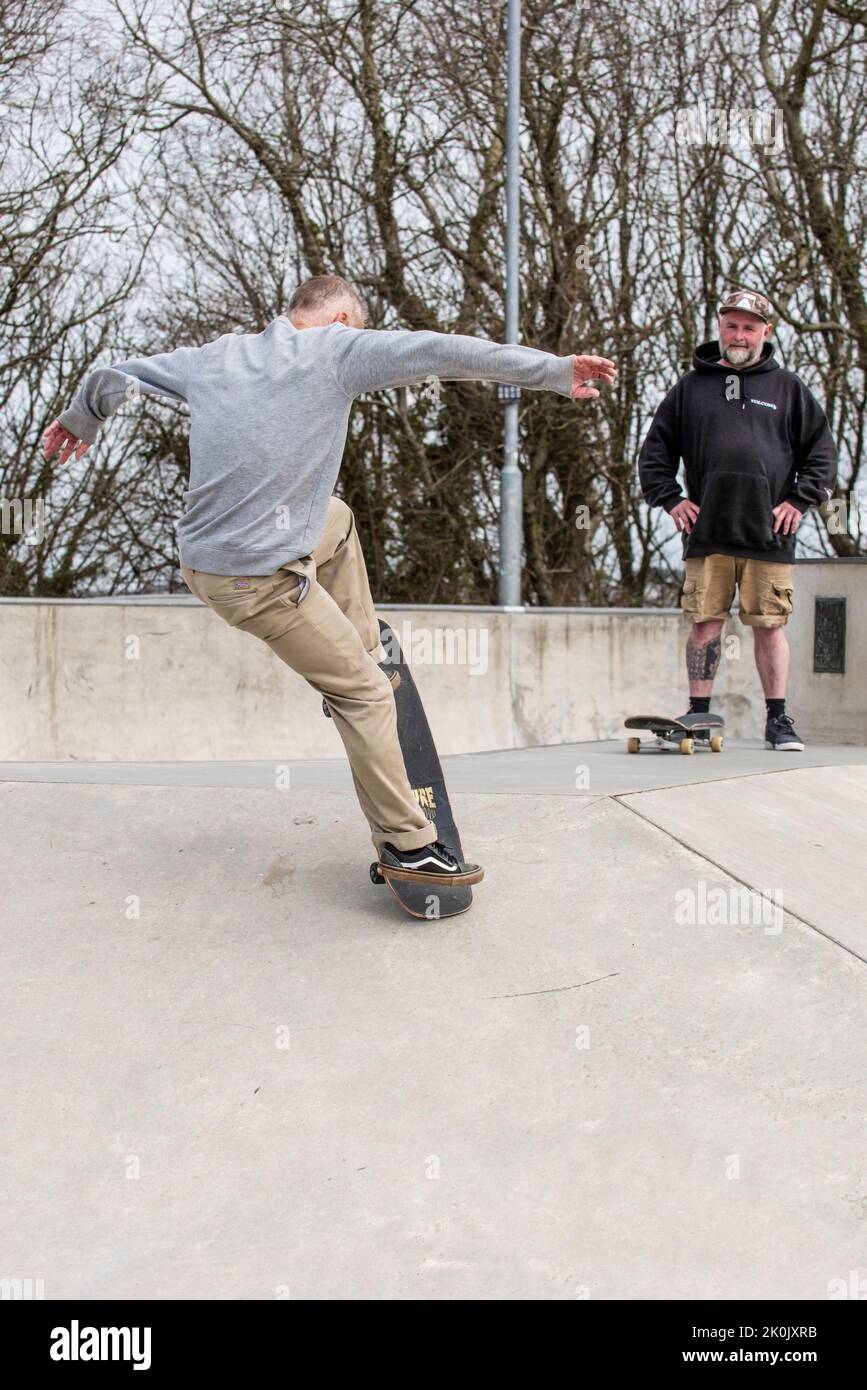 Uno skateboarder maschile maturo che esegue un trucco al Newquay concrete Waves Skatepark di Newquay in Cornovaglia nel Regno Unito. Foto Stock