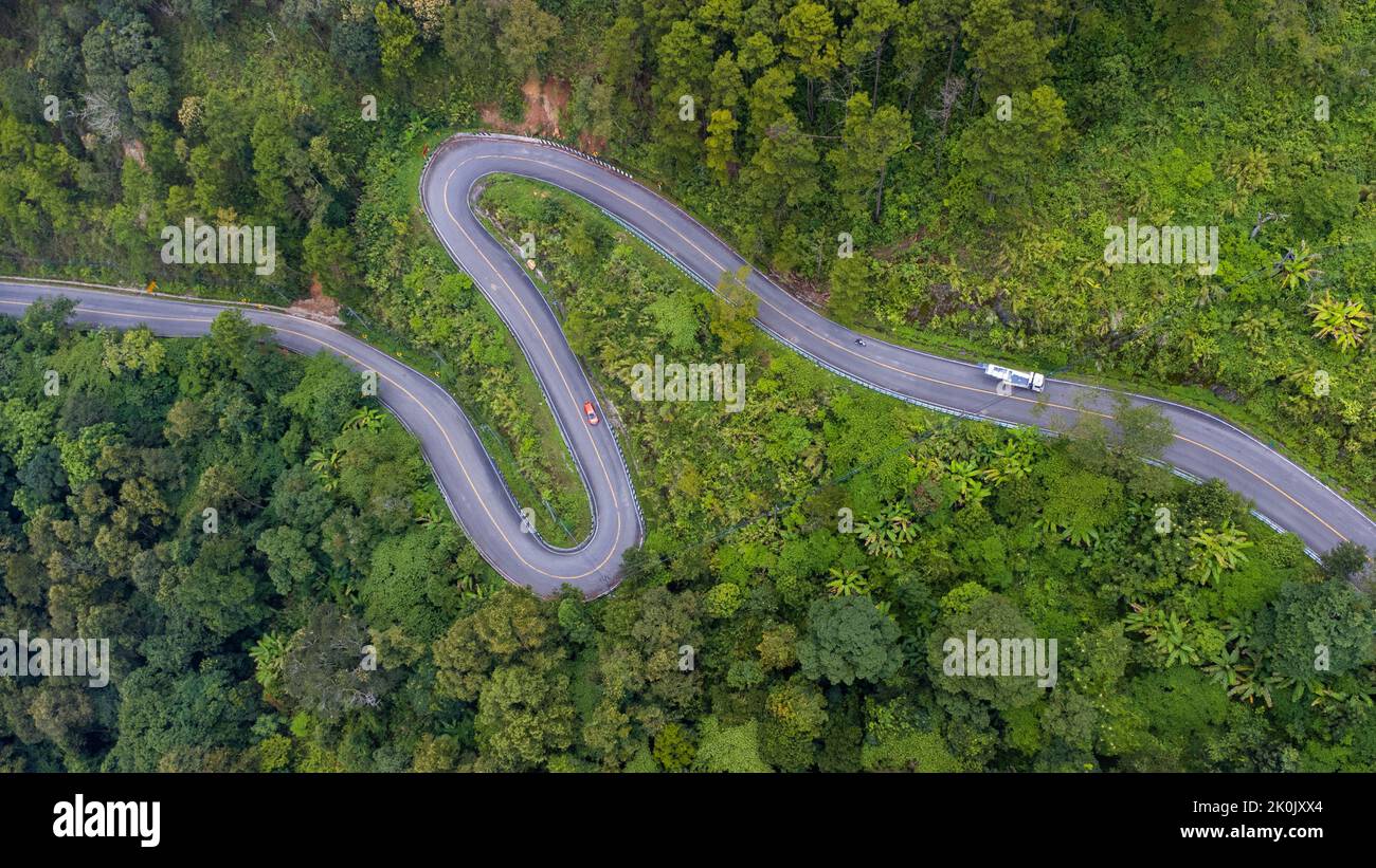 Veduta aerea di una strada collinare con belle foreste verdi in Thailandia. Acquisizione aerea con drone. Foto Stock