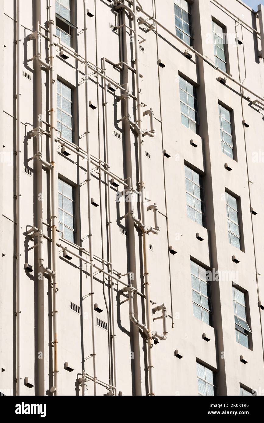 Visto raramente negli edifici australiani, i tubi dell'acqua esterni e l'impianto idraulico corrono su e giù per il lato di questo edificio nel centro di Sydney, Australia Foto Stock