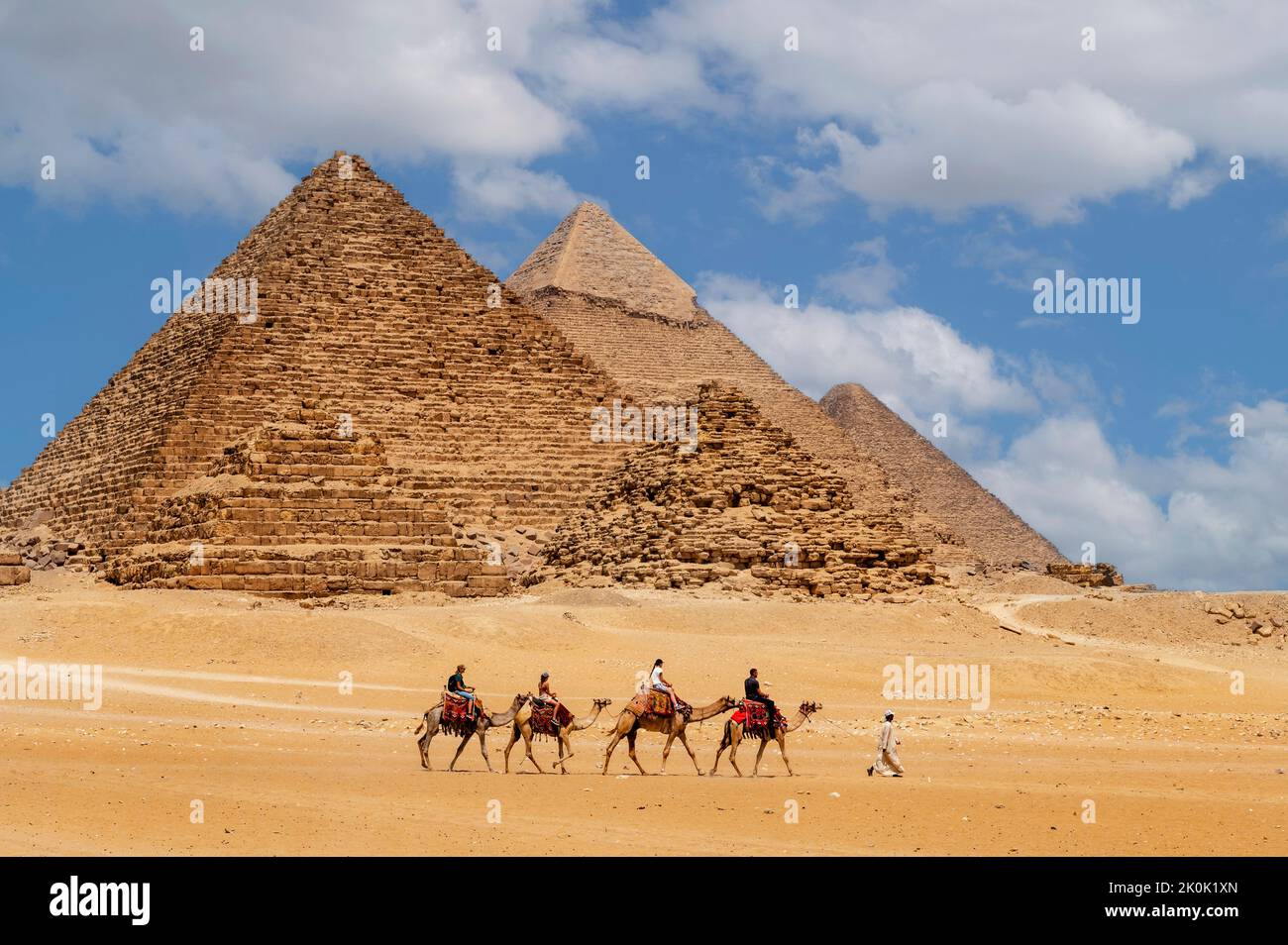Cairo, Egitto. 08.25.2022. Gruppo di turisti in sella a cammelli che vedono le piramidi di Menkaure, Chefren e Cheope. Foto Stock