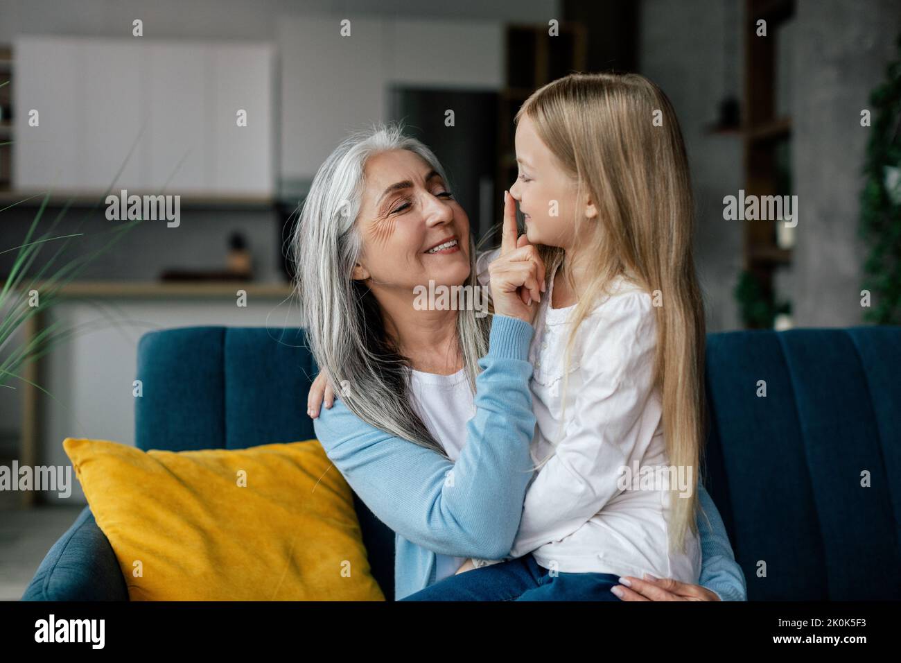 La nonna sorrida europea abbraccia la nipote piccola, tocca il naso, goditi il tempo libero Foto Stock