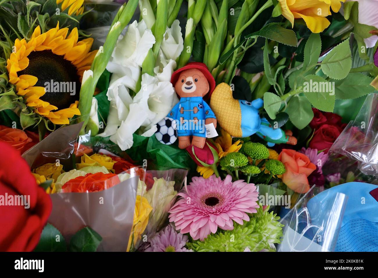 Bouquet, tributi scritti, giocattoli coccolati, candele e carte sono stati deposti in onore della tarda Regina Elisabetta a Green Park e migliaia di persone hanno continuato a affollarsi alla residenza reale Buckingham Palace nel centro di Londra. Foto Stock