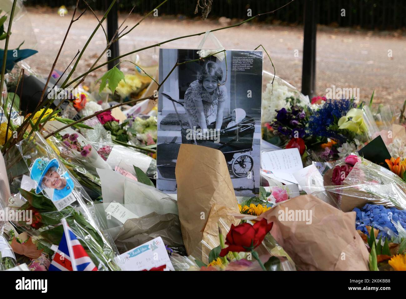 Bouquet, tributi scritti, giocattoli coccolati, candele e carte sono stati deposti in onore della tarda Regina Elisabetta a Green Park e migliaia di persone hanno continuato a affollarsi alla residenza reale Buckingham Palace nel centro di Londra. Foto Stock