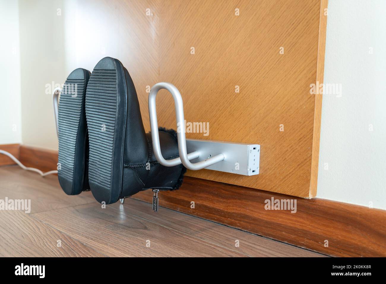 Primo piano sulle scarpe che vengono asciugate su un asciugatore elettrico in una composizione asimmetrica Foto Stock