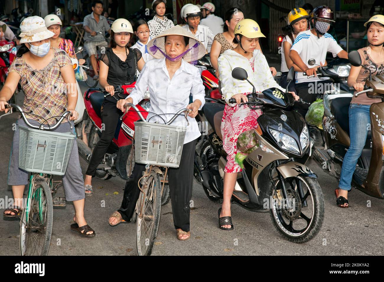 Motociclisti e ciclisti in attesa al bivio stradale, Hai Phong, Vietnam Foto Stock