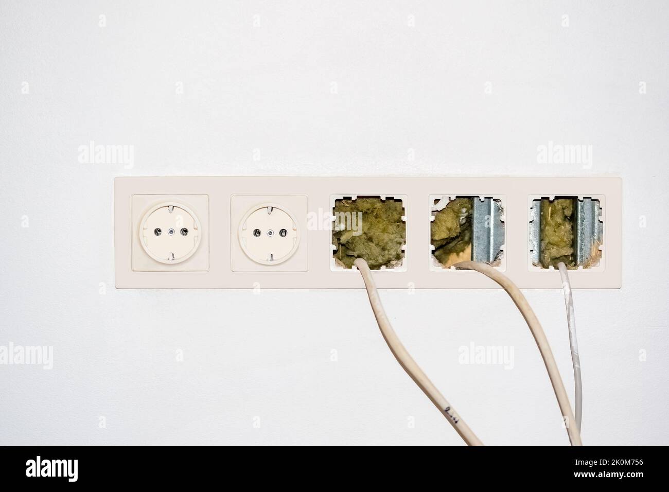 Presa elettrica bianca con interruttori e fili sporgenti su una parete bianca Foto Stock