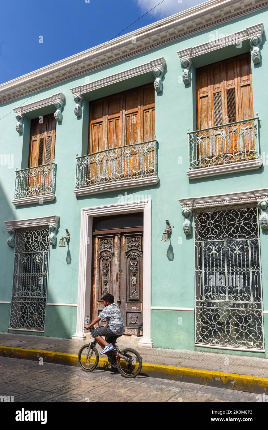 Ciclista guida di fronte ad un edificio coloniale, Merida Messico Foto Stock