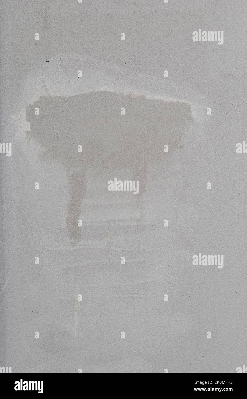 Vista frontale di una parete in pietra grigia intonacata e danneggiata con macchie provenienti dalla rimozione dei graffiti. Sfondo strutturato astratto ad alta risoluzione. Foto Stock
