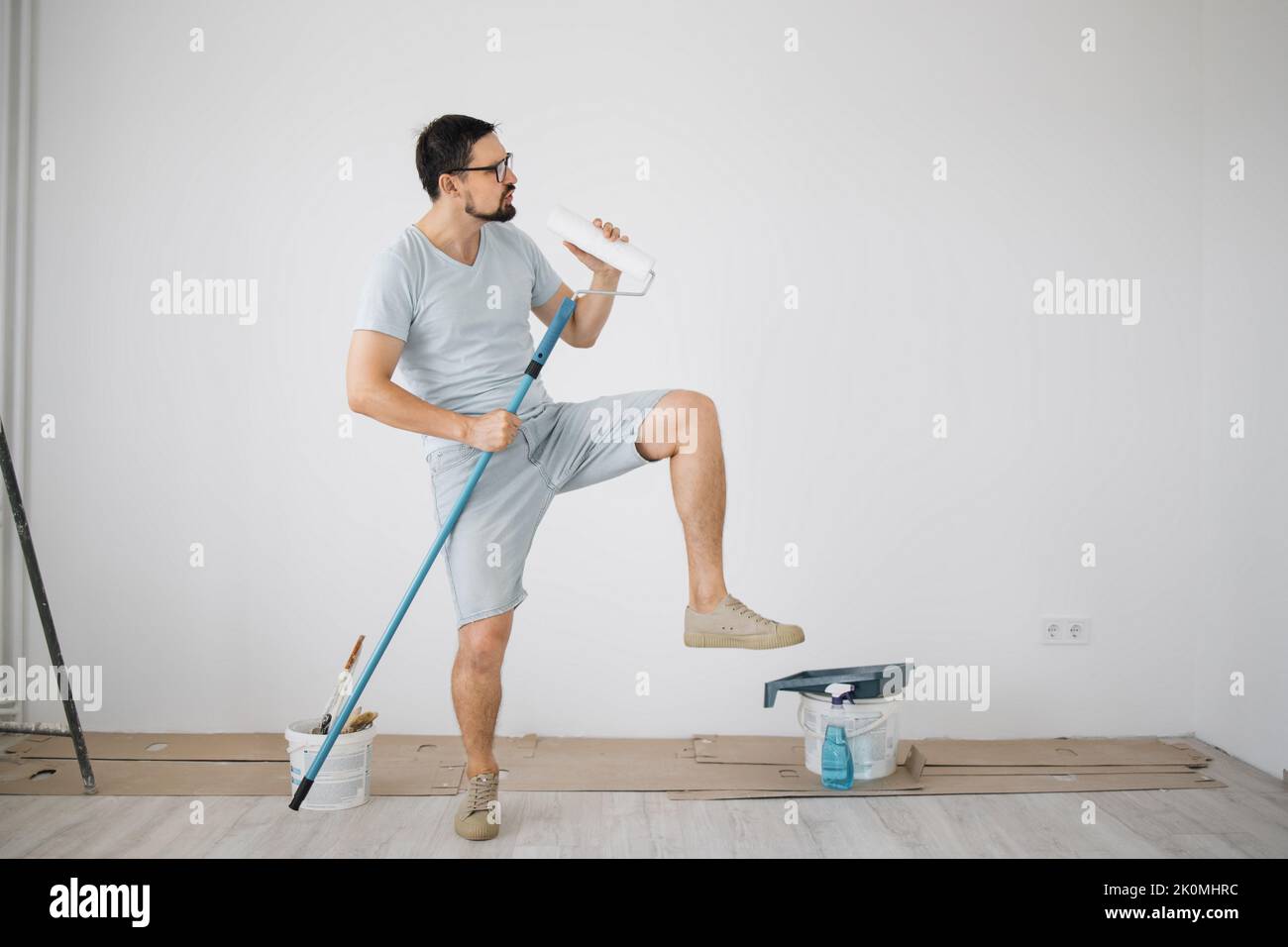 Giovane, che ha finalmente raccolto l'importo necessario per le riparazioni, gioire e ballare. Invece di un vero microfono, un ragazzo che usa in un mop e un rullo di vernice. Foto Stock