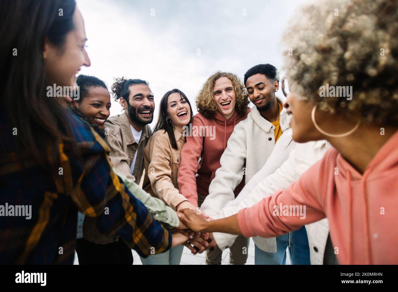 Felice giovane gruppo di persone multirazziali che accatastano le mani all'aperto Foto Stock