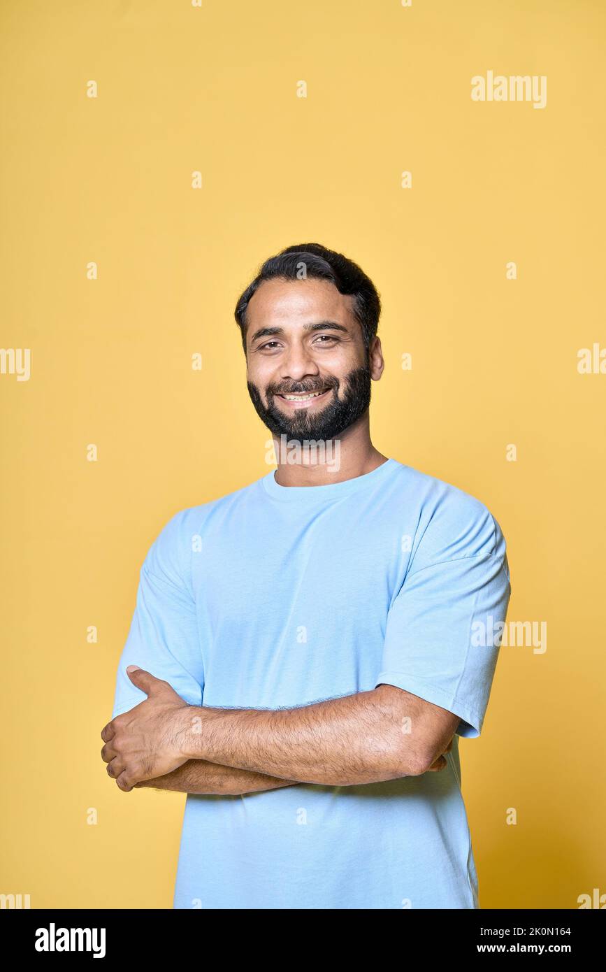 Sorridente uomo indiano sicuro in piedi isolato su sfondo giallo, verticale. Foto Stock