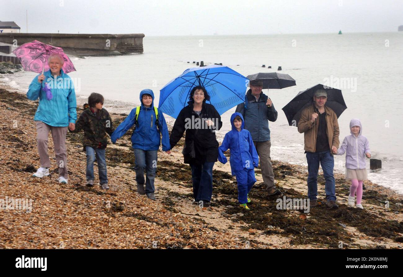 LA FAMIGLIA CHOWDY DEL GALLES NON HA LASCIATO LA PIOGGIA SMORZARE I LORO SPIRITI IN UNA VISITA ALLA SPIAGGIA SULLE FESTE DI LUNEDÌ A SOUTHSEA, HANTS.2014 PIC MIKE WALKER, MIKE WALKER IMMAGINI Foto Stock