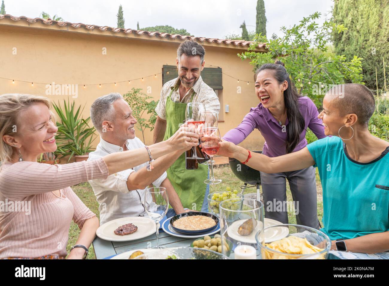 Gli uomini e le donne di mezza età felici allietano al picnic della casa di campagna. Concetto di stile di vita con amici allegri divertirsi insieme nel pomeriggio rilassante Foto Stock