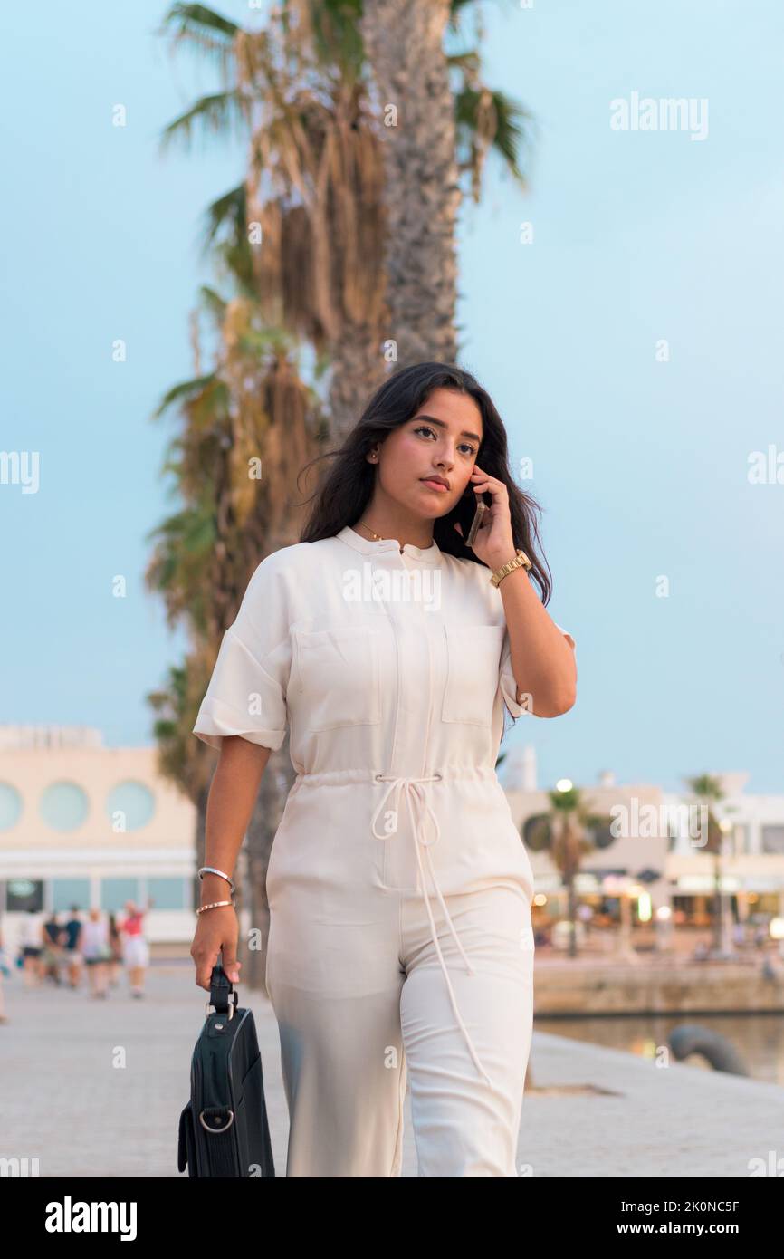 La giovane donna latina parla attraverso il suo telefono cellulare all'esterno Foto Stock