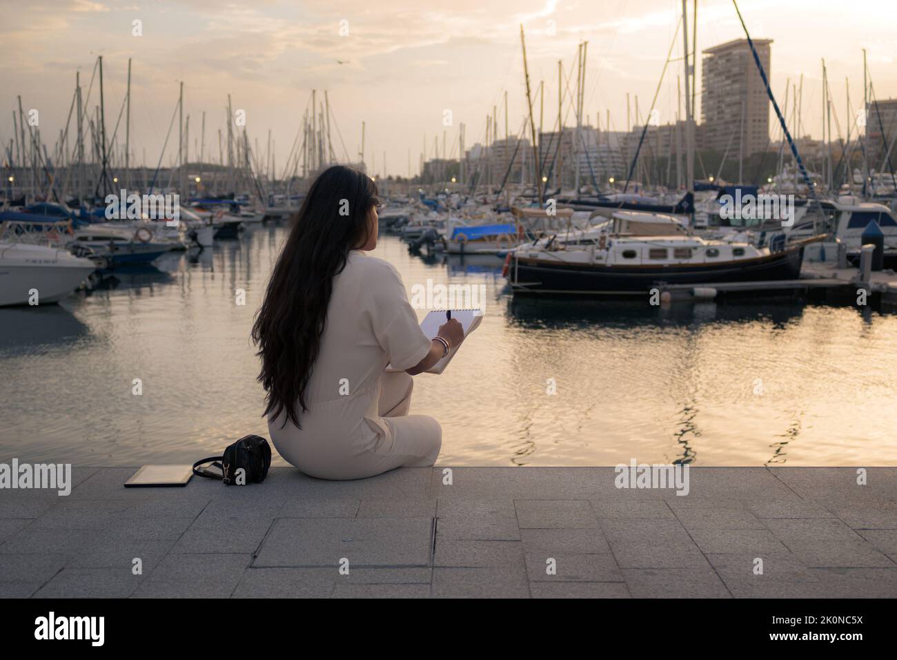 Donna sulla schiena che lavorava seduto con vista su un porto Foto Stock
