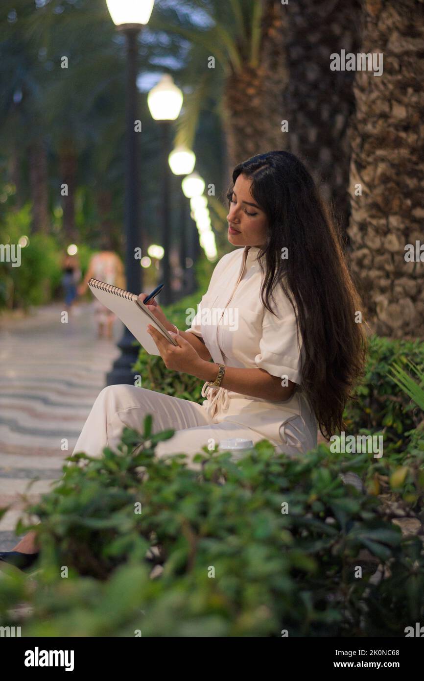 Bella donna latina business scrivere in un notebook di notte Foto Stock