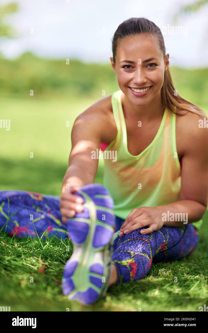 Lo stretching è importante quanto l'esercitazione. Una giovane donna che allunga le gambe prima di un workout. Foto Stock