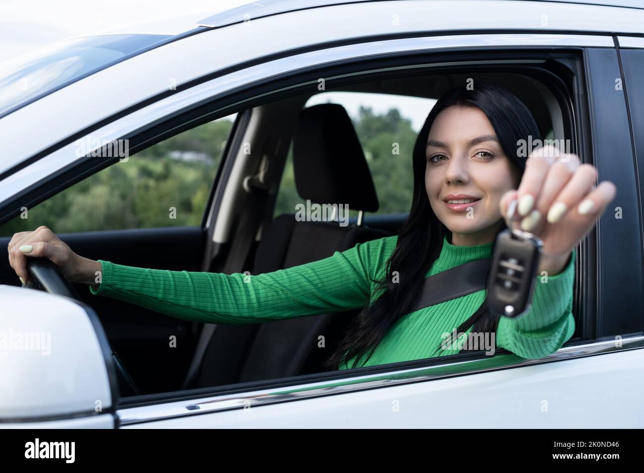 Sorridente giovane donna dà le chiavi dell'automobile a qualcuno. Conducente in auto. La mia patente di guida è scaduta. Foto Stock