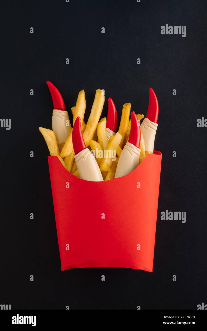 Patatine fritte con ketchup e dita di strega in scatola di carta rossa isolata su fondo nero. Horror concept di Halloween. Idea spaventosa e spoky. Foto Stock