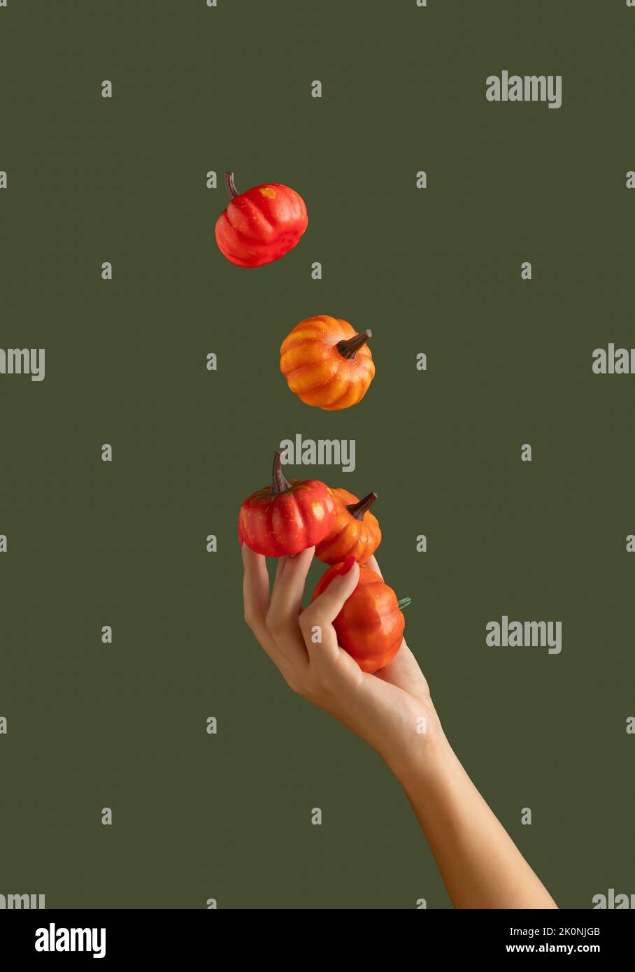 Bella donna che giocolano le zucche su sfondo verde scuro. Colori autunnali. Concetto minimo di Halloween. Foto Stock