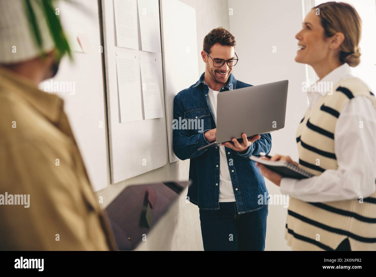 Buon businesspeople che analizza alcuni rapporti su una bacheca di avviso durante una riunione in un ufficio creativo. Gruppo di uomini d'affari diversi che lavorano in team Foto Stock