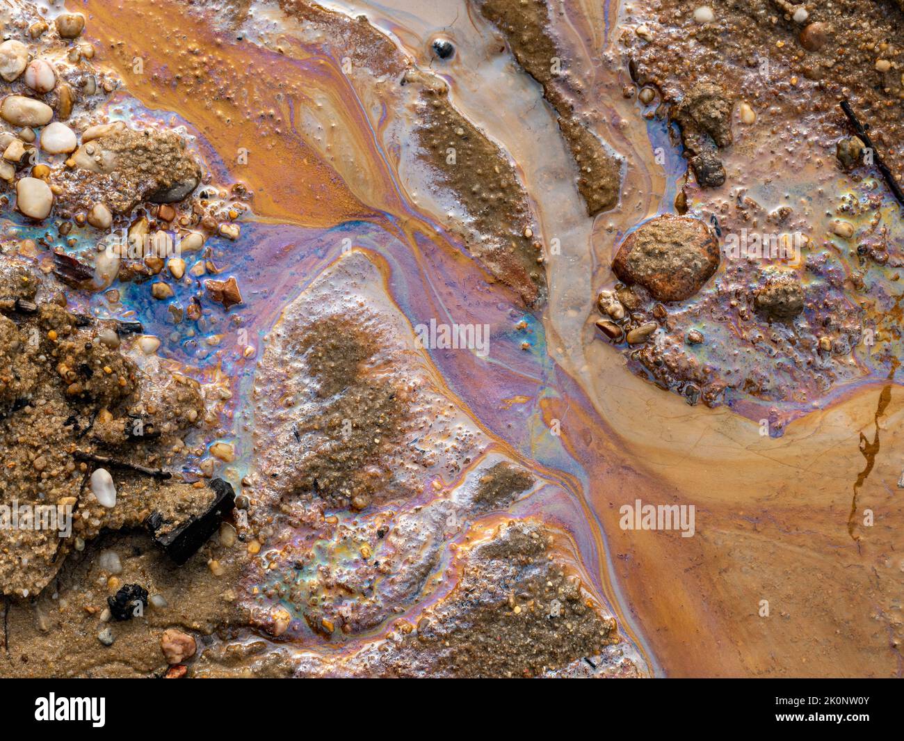 Inquinamento da fuoriuscite di petrolio nell'acqua e sulla sabbia. Combustibile fossile nell'ambiente. Sono visibili i colori spettrali della luce. La natura è contaminata. Foto Stock