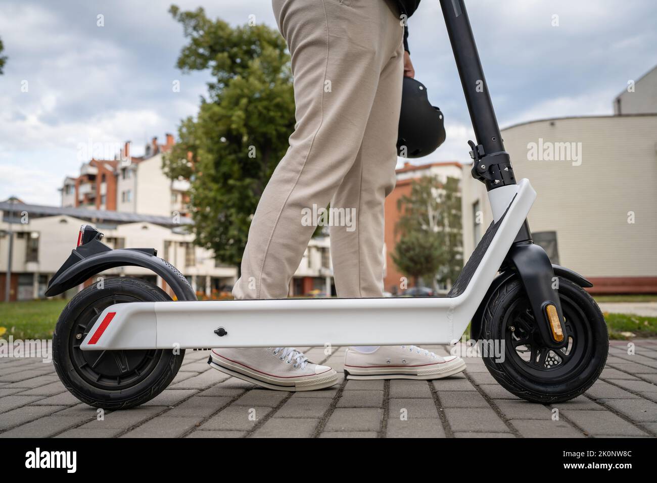 Piedi di un uomo sconosciuto in piedi o alla guida di scooter elettrici calcio e-scooter sul marciapiede in giorno ecologico moderno trasporto Foto Stock