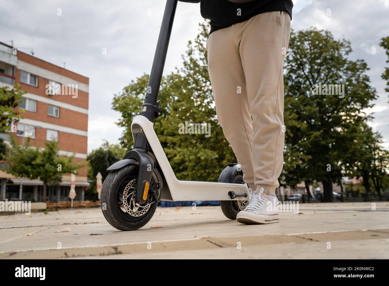 Piedi di un uomo sconosciuto in piedi o alla guida di scooter elettrici calcio e-scooter sul marciapiede in giorno ecologico moderno trasporto Foto Stock