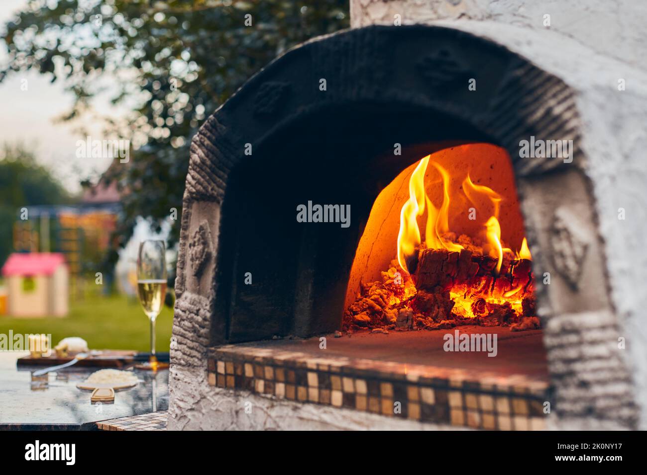 Forno a legna per pizza con tronchi di betulla per l'accensione. Il fuoco brucia e il forno si riscalda. Vista frontale. Foto Stock Forno a legna per pizza con tronchi di betulla per l'accensione. Il fuoco brucia e il forno si riscalda. Vista frontale. Foto Stock