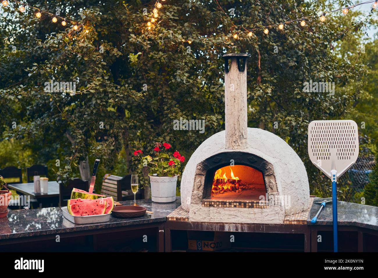 Forno a legna per pizza con tronchi di betulla per l'accensione. Il fuoco brucia e il forno si riscalda. Vista frontale. Foto Stock Forno a legna per pizza con tronchi di betulla per l'accensione. Il fuoco brucia e il forno si riscalda. Vista frontale. Foto Stock