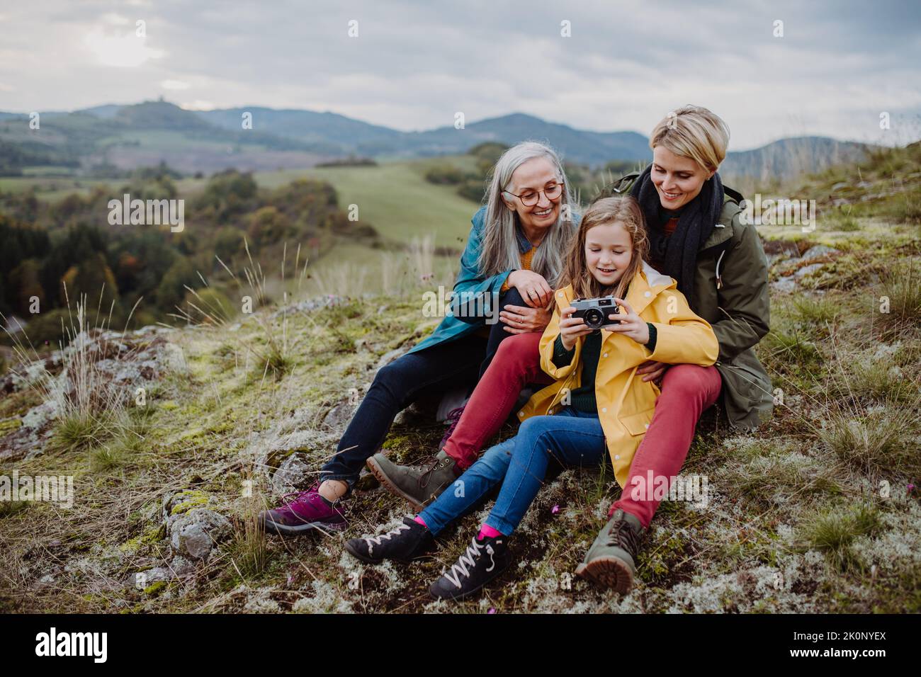 Donna anziana fotografando la figlia e la nipote in cima alla collina nel giorno d'autunno. Foto Stock