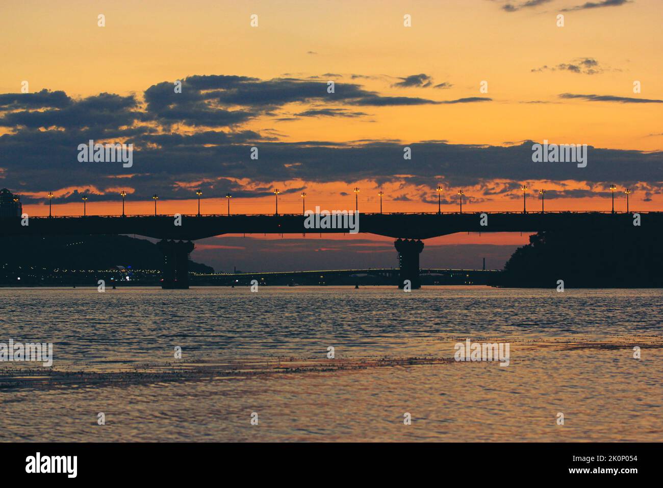 Bella silhouette ponte auto a contrasto al tramonto, al crepuscolo, al crepuscolo serale. Contrasto multicolore giallo-rosso-blu cielo nuvoloso. Panorama di Foto Stock